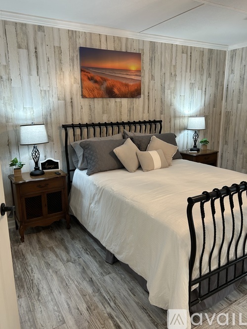 A bedroom with a large bed and a painting on the wall.