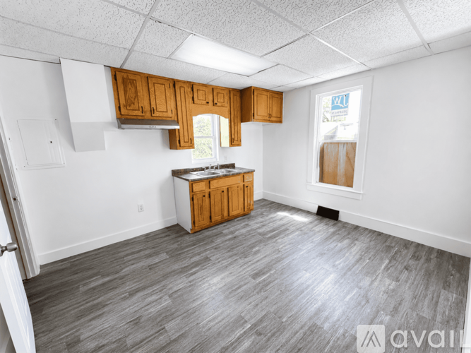 A kitchen with wooden cabinets and a grey floor.