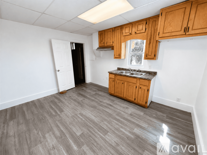 A kitchen with wooden cabinets and a black refrigerator.