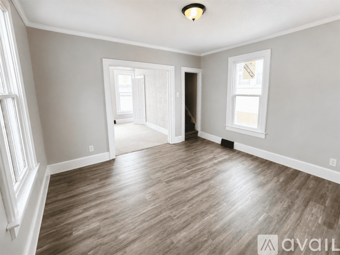 A spacious room with wood flooring and white walls.