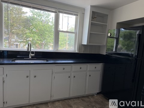 A kitchen with white cabinets and a black countertop.