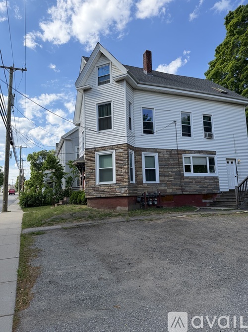 A two-story house with a white exterior and a brick foundation.