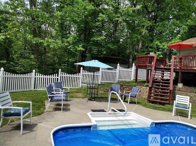A pool with a white fence and chairs around it.