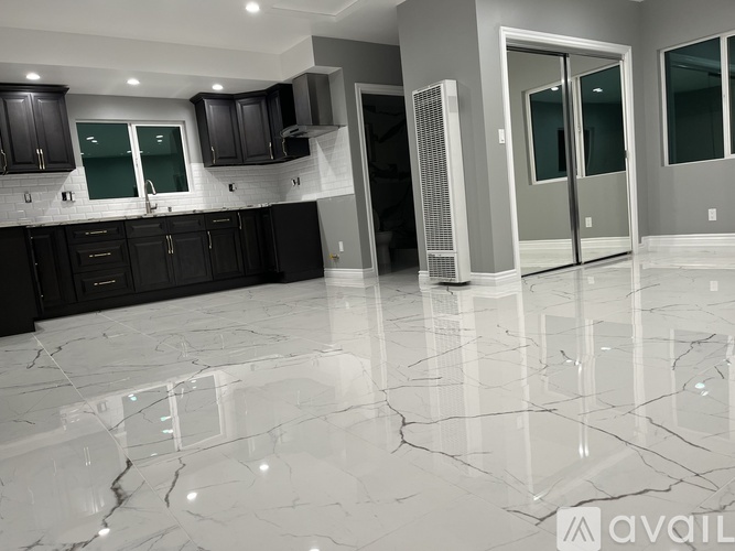 A kitchen with black cabinets and a marble floor.