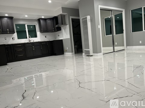 A kitchen with black cabinets and a marble floor.