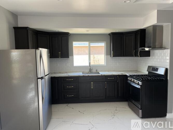 A kitchen with black cabinets and a stainless steel refrigerator.