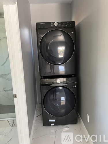 A black front load washing machine and dryer in a small laundry room.