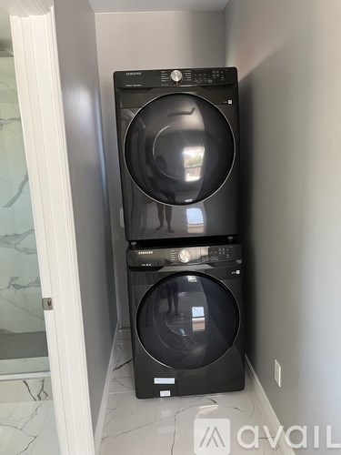A black front load washing machine and dryer in a small laundry room.