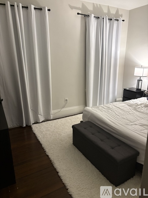 A bedroom with a bed, nightstand, and a rug.