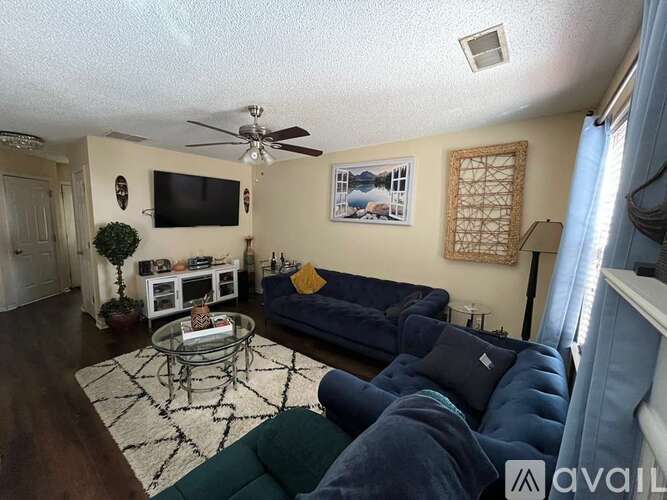 A living room with a blue couch and a television on the wall.