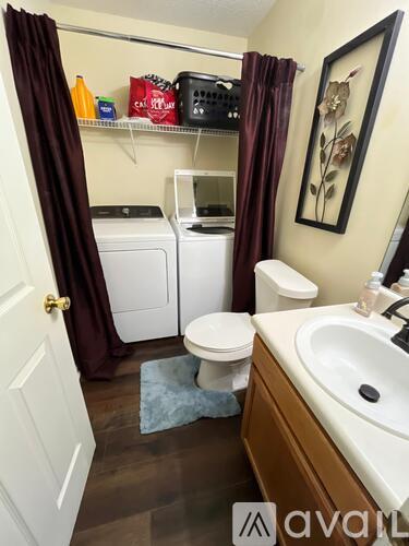 A small bathroom with a toilet, sink, and washer and dryer.