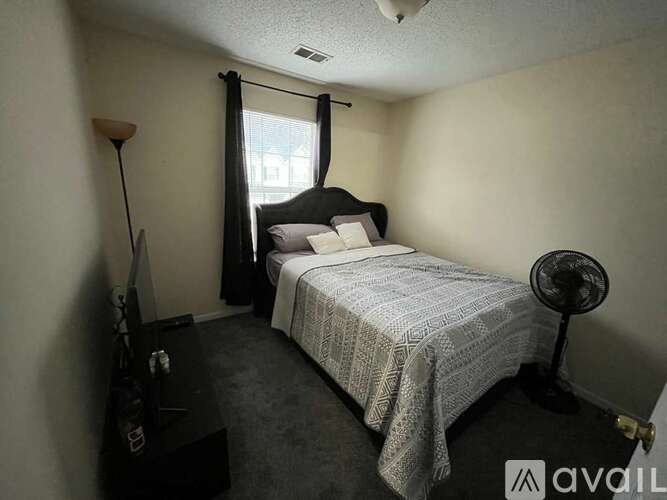 A bedroom with a bed, nightstand, and a fan.