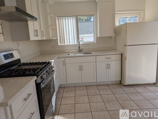A kitchen with white cabinets and a black stove top.