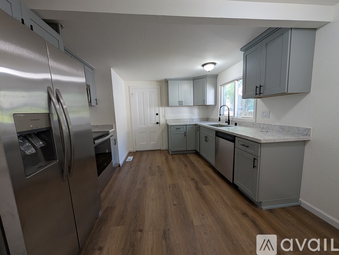 A kitchen with a refrigerator, cabinets, and a countertop.