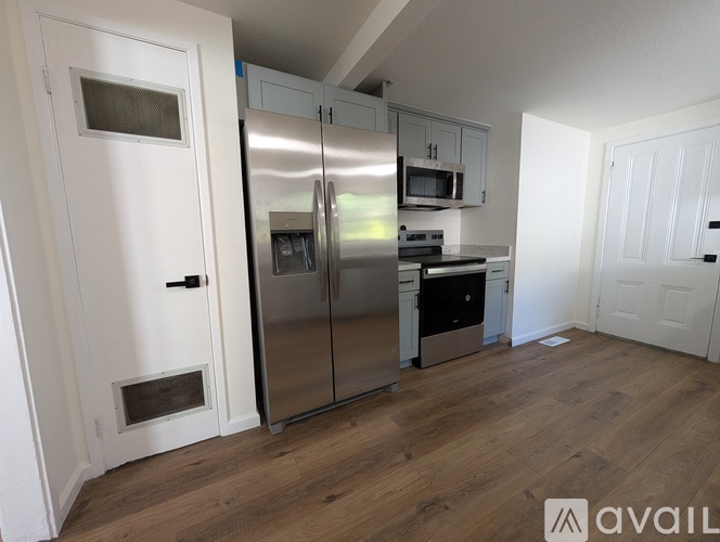 A kitchen with a refrigerator, microwave, and oven.