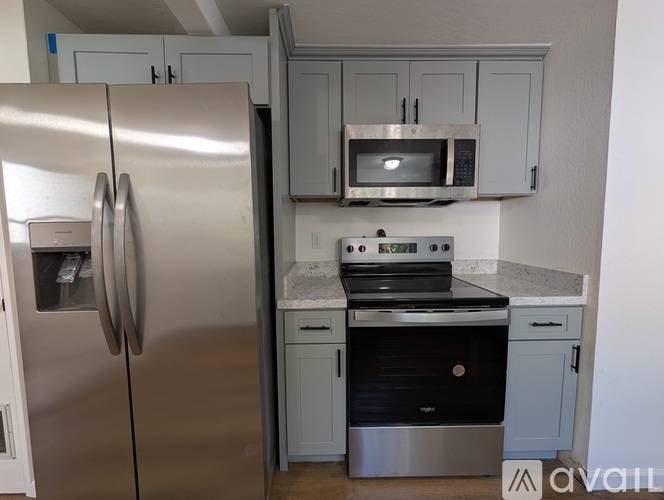 A kitchen with a stainless steel refrigerator, microwave, oven, and cabinets.