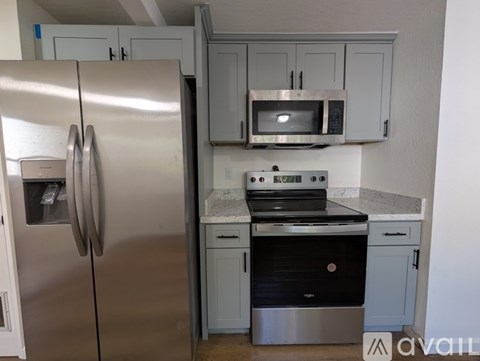 A kitchen with a stainless steel refrigerator, microwave, oven, and cabinets.