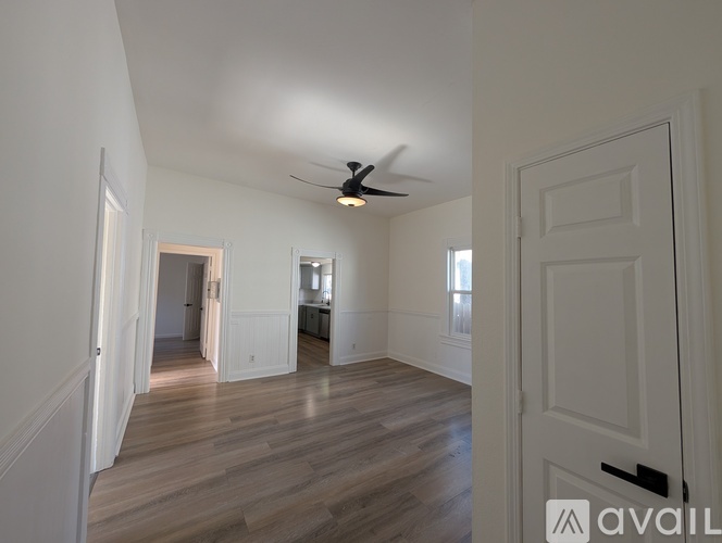 A spacious room with wooden floors and a ceiling fan.