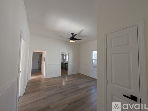 A spacious room with wooden floors and a ceiling fan.