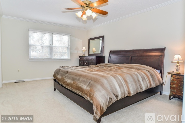 A bedroom with a large bed and a ceiling fan.