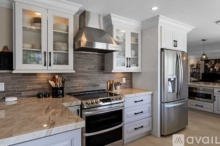 A modern kitchen with a stainless steel refrigerator and a marble countertop.