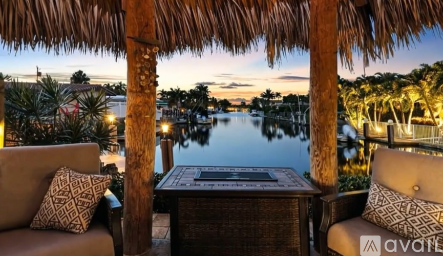 A table with a plaque on it is in the middle of a patio with two chairs and a view of a body of water.