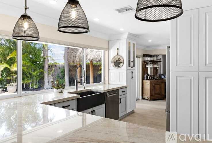 A modern kitchen with a large island and pendant lights.