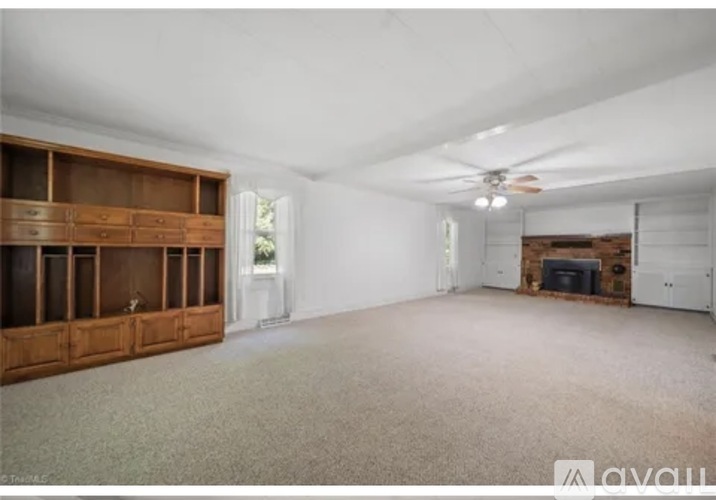 A spacious room with a ceiling fan and a fireplace.