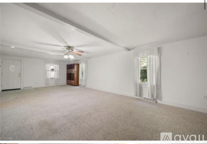 A spacious room with a ceiling fan and carpeted floor.