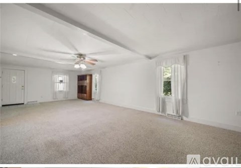 A spacious room with a ceiling fan and carpeted floor.