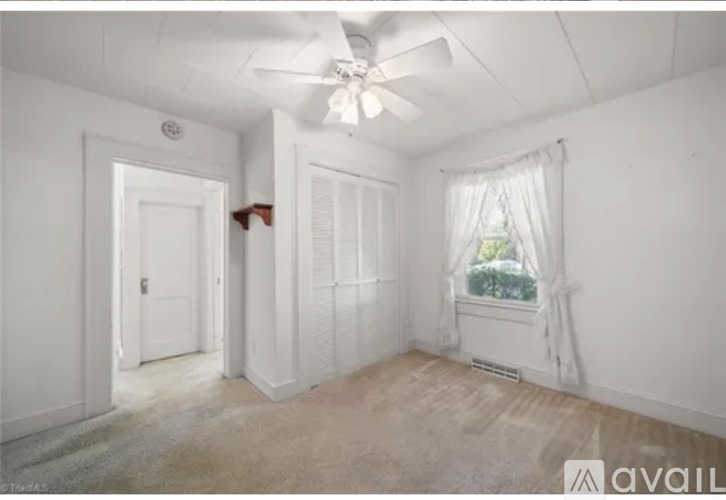 A room with a ceiling fan and a window with curtains.