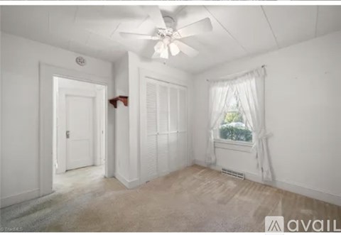 A room with a ceiling fan and a window with curtains.