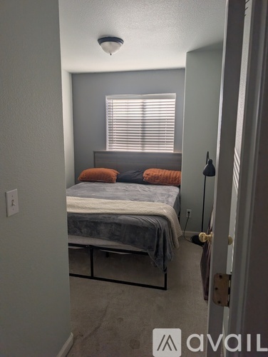 A bedroom with a bed, pillows, and a nightstand.
