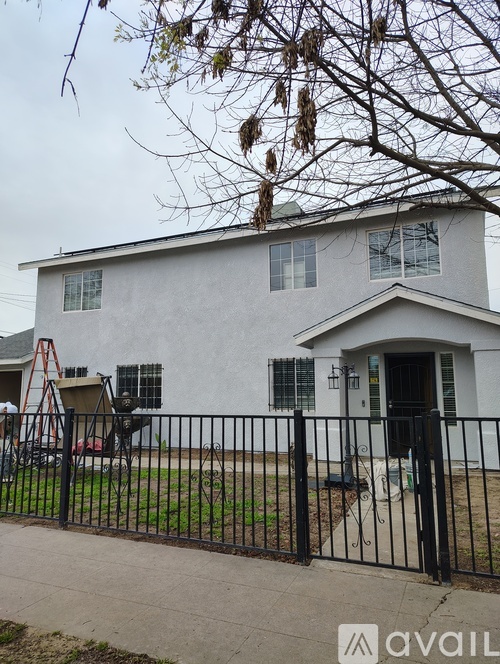 A white house with a black fence in front.