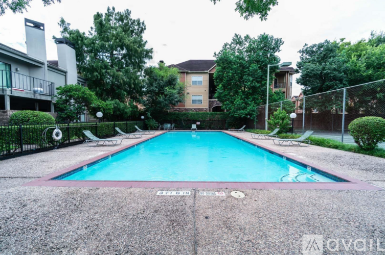 A pool surrounded by a fence and trees.