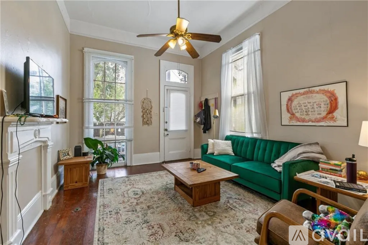 A living room with a green couch and a ceiling fan.