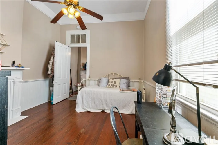 A bedroom with a white bed and a ceiling fan.