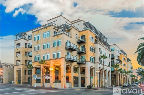 A modern apartment building with balconies and a street in front.