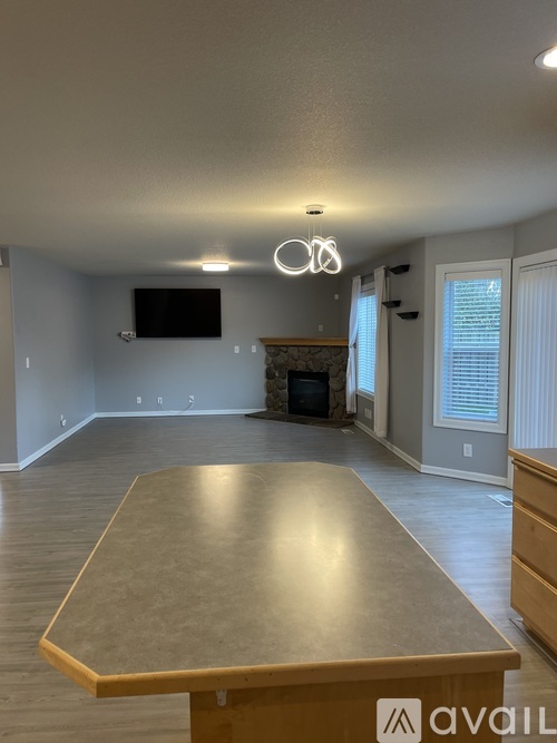 A spacious room with a large table in the foreground and a fireplace in the background.