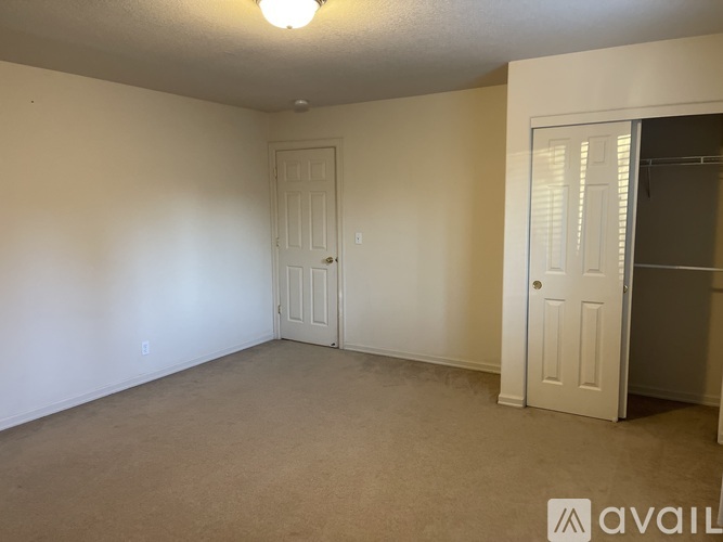 A room with a carpeted floor, two doors, and a ceiling light.