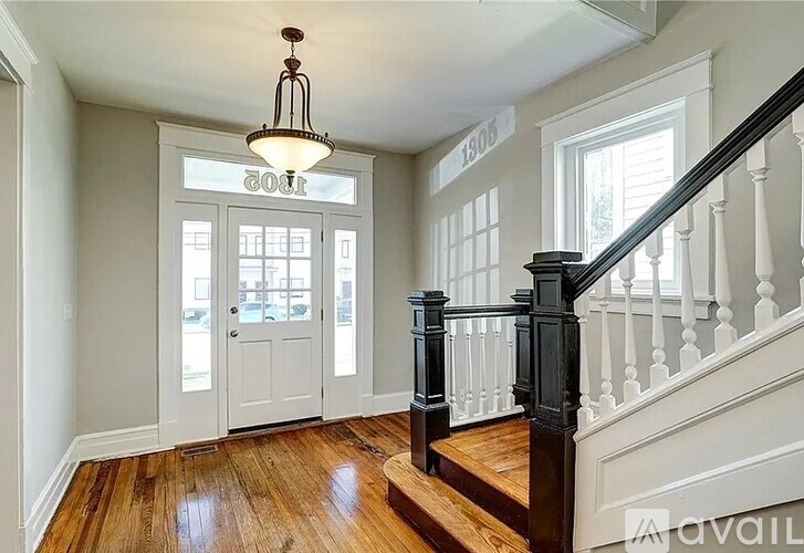 A wooden staircase with a black railing and a chandelier hanging from the ceiling.