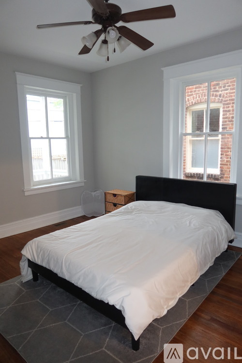 A bedroom with a bed, a ceiling fan, and a window.