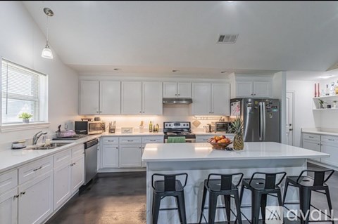 A kitchen with white cabinets and a white island with a pineapple on it.