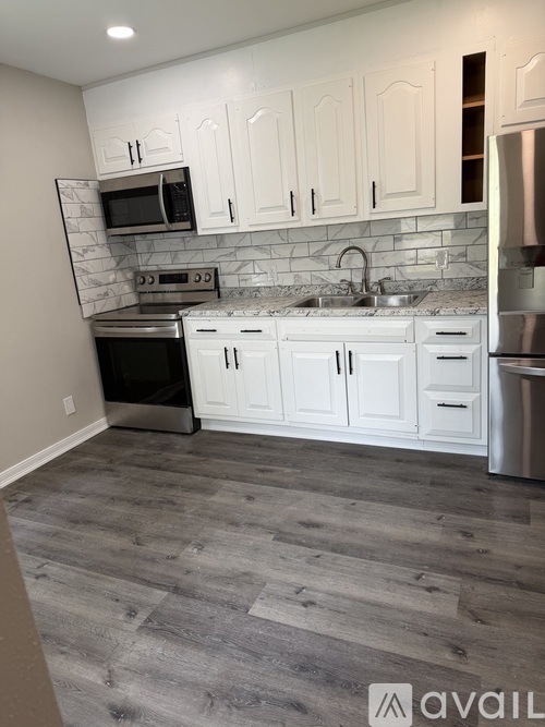 A kitchen with white cabinets and a marble backsplash.