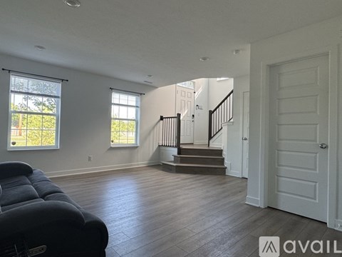 A living room with a black couch and a staircase leading to the upper floor.