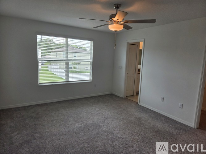 A room with a ceiling fan and a window with blinds.