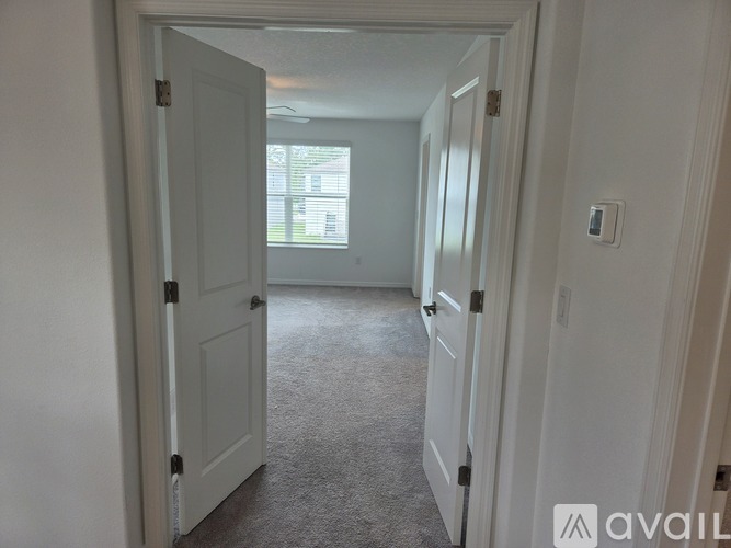 A hallway with white doors and carpeted floor.