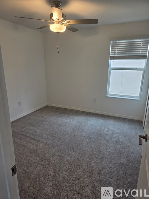 A room with a ceiling fan and carpeted floor.