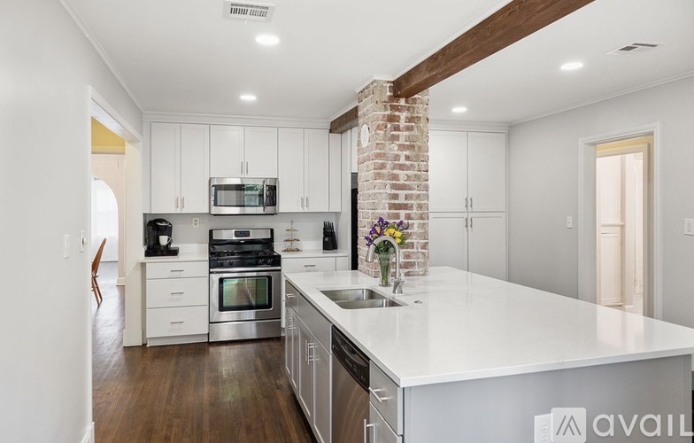 A kitchen with white cabinets and a brick column.