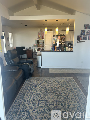 A living room with a black couch and a rug.
